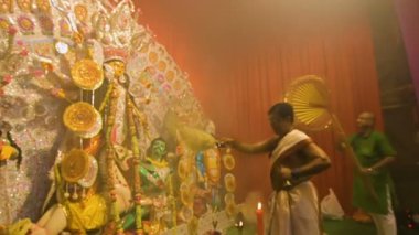 Kolkata, Hindistan -13 Ekim 2021: Hindu rahipler tanrıça Durga 'ya ghanta, chamor ve el yelpazesiyle tapıyorlar. Ashtami puja aarati - kutsal Durga Puja ritüeli - gece çekildi. 4K video.