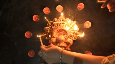 Indian woman lighting up diwali candles or diya put in circle. Deepawali lights at night. Dark background stock footage.