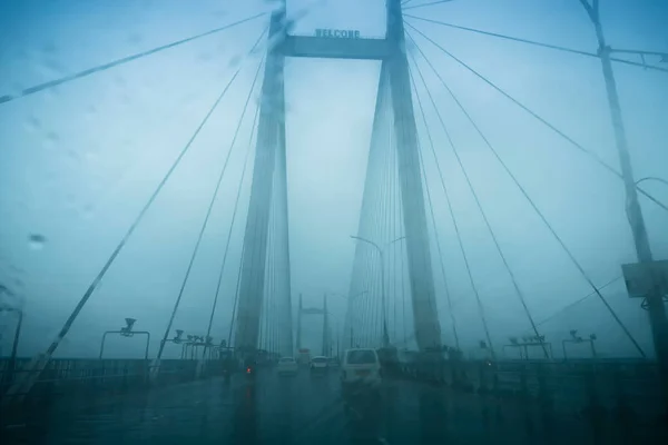 Vidyasagar Setu (Bridge) over river Ganges, known as 2nd Hooghly Bridge in Kolkata,West Bengal, India. Abstract image shot aginst glass with raindrops all over it, monsoon image of Kolkata.