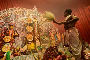 Howrah, Hindistan -13 Ekim 2021: Hindu Rahipler Tanrıça Durga 'ya Ganta, chamor ve el yelpazesiyle tapıyorlar. Ashtami puja aarati - kutsal Durga Puja ritüeli - gece çekildi.