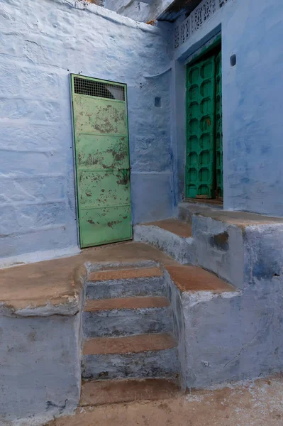 Traditional green wooden door and blue coloured house of Jodhpur city, Rajsthan, India. Historically, Hindu Brahmins used to paint their houses in blue for being upper caste, the tradition follows.