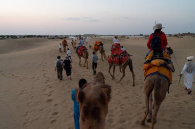 Thar Çölü, Rajassthan, Hindistan - 15 Ekim 2019: Thar Çölü 'nün kum tepelerinde deveye binen turistler. Deve sürmek burayı ziyaret eden tüm turistler arasında favori bir etkinliktir.,
