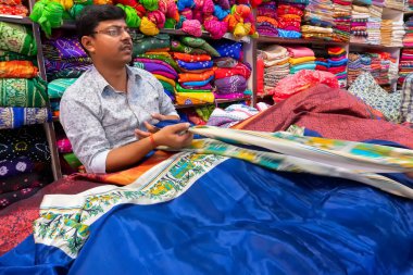 Jaisalmer, Rajasthan, Hindistan - 15 Ekim 2019: Sari satıcı müşterilere sari satıyor, güzel renkli Hint sarileri pazar yeri Jaisalmer, Hindistan 'da satışa sunuluyor.