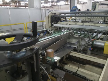 Kolkata, West Bengal, India - 16th May 2019 : Manufactured white Paper sheets are being slitted and rewinded in paper slitting and rewinding machine. in a paper manufacturing plant.