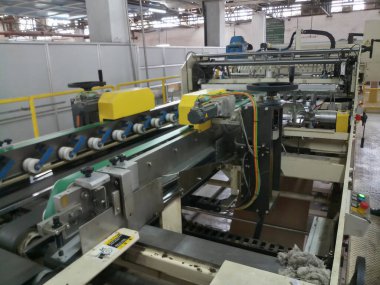 Kolkata, West Bengal, India - 16th May 2019 : Manufactured white Paper sheets are being slitted and rewinded in paper slitting and rewinding machine. in a paper manufacturing plant.