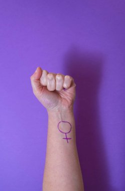 Mor arka planda koluna kadın sembolü çizilmiş bir kadın yumruğu. Feminizm ve feminist aktivizm kavramı