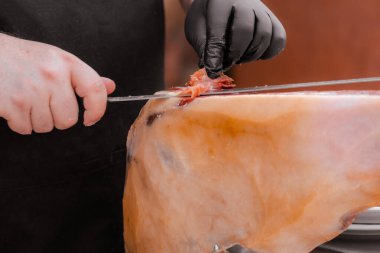 Profesyonel Iberico ya da Serrano jambonu dilimlenmiş domuz bacağını jambon bıçağıyla kesiyor.