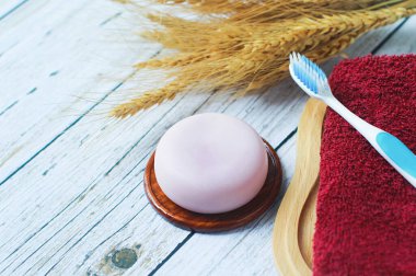 Eski ahşap zemine konmuş el yapımı bitkisel gliserin sabunu, havlular ve diş fırçaları sağlanıyor..