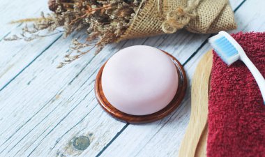 Eski ahşap zemine konmuş el yapımı bitkisel gliserin sabunu, havlular ve diş fırçaları sağlanıyor..