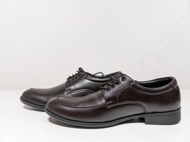 Beyaz arkaplanlı bağcıklı bir çift siyah ayakkabı.