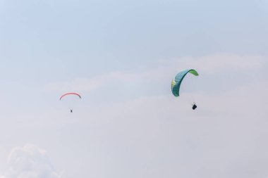 Gökyüzünde güzel mavi gökyüzü ve arka planda sarmalanmış paraşütçüler.