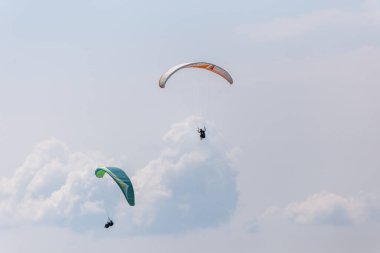 Gökyüzünde güzel mavi gökyüzü ve arka planda sarmalanmış paraşütçüler.