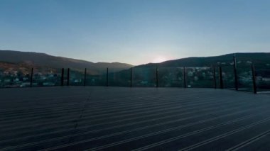 Dağların ardında güneş batıyor. Büyük bir balkondan harika bir manzara..