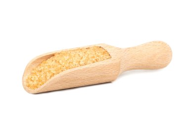 Beyaz arka planda izole edilmiş tahtadan bir kepçedeki kahverengi şeker.