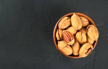 Koyu beton arka planda kuru kabuklu ceviz dolu seramik kase, boşluğu kopyala.