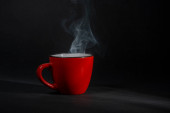 Kouřící káva červený šálek na tmavém pozadí