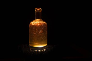 Koyu kahverengi sıvı şişe, kırılma ve koyu arkaplanda röfle.
