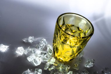 Bir kap, koni şeklinde renkli bir cam. Dış çevre boyunca hacimsel kenarları var. Tabanında renkli gölgeler olan değişken ışıklandırma derecelerinin gri arkaplanı