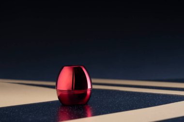 Çizgili bir tabanda metalik yansımalı parlak kırmızı kutu.