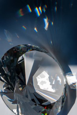 Elmas şeklinde cam prizma. İçinden geçen parlak kenarlar ve ışık lekeleri var.