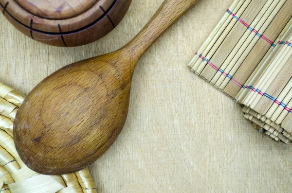 Tahta arka planda bambu hasırı ve tahta kaşık.