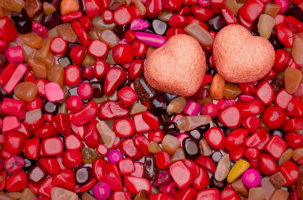 Kırmızı taşların üzerinde iki tatlı kalp, arka planda sevgililer günü düzdü.