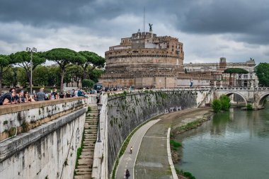 Roma, İtalya - 6 Mayıs 2018: Adriano Parkı 'ndaki Castel Sant Angelo ya da Hadrian Anıtmezarı olarak bilinen Kutsal Melek Şatosu Tiber üzerinde bir köprüye ve bulutlu bir günde toprak seti bulunan.