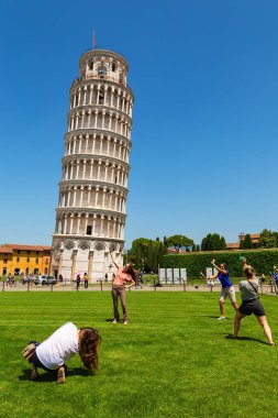 Pisa, Tuscany, Italy - May 23, 2022: Tourists posing in front of the famous Leaning Tower of Pisa. The italian name is Torre pendente di Pisa, at Pisa Cathedral Square (Piazza del Duomo).