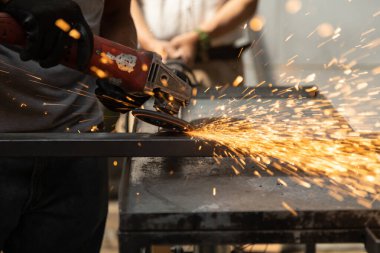 Metal cilası kullanırken siyah koruyucu eldiven takan birinin eline yakın çekim, maquiladan kıvılcımlar, fabrikada el işi.