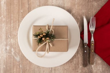 Güzel bir Noel süslemesi. Metal çatal bıçak takımı, kırmızı peçete ve üstünde süs olan bir tabak.