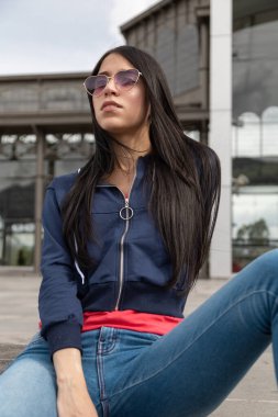 Uzun, düz siyah saçlı genç bir Latin kadını poz vermek, gündelik bir ceket ve kalp şeklinde gözlük takmak, yaşam tarzı, güzellik ve moda