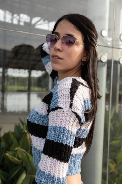 Yaz günü çekici, uzun saçlı, poz verirken eğlenen, güneş gözlüğü takan, doğal makyaj yapan, günlük kıyafetler giyen, aksesuarlı moda ve güzel bir kadın.