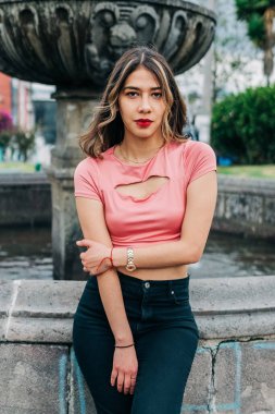 Uzun dalgalı sarı saçlı çekici Latin kadın, kameraya bakıyor, kırmızı dudaklı ve gölgeli makyaj yapıyor, gençlik modası, güzellik