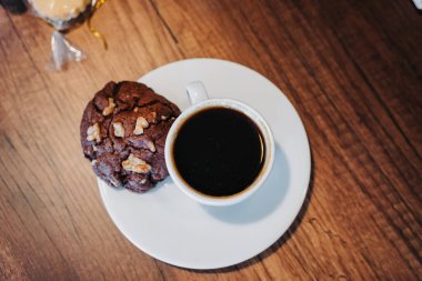 Tahta bir masada servis edilir, bir fincan kahve ve bir tabak çikolata parçalı kurabiye, içecek ve tatlı yemek, kafeterya yaşam tarzı, lezzetli pişmiş yiyecekler.