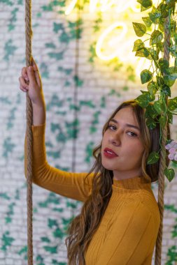 Makyajlı yüz ayrıntıları ve sarı saçlı genç Latin bir kadının kırmızı dudakları. Bitki arkaplanlı güzellik modeli.