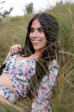 Yüzü buruşuk, siyah saçlı, renkli bluz giyen, jestleri olan neşeli bir hayat tarzı olan, doğal güzelliği olan genç Latin bir kadın.