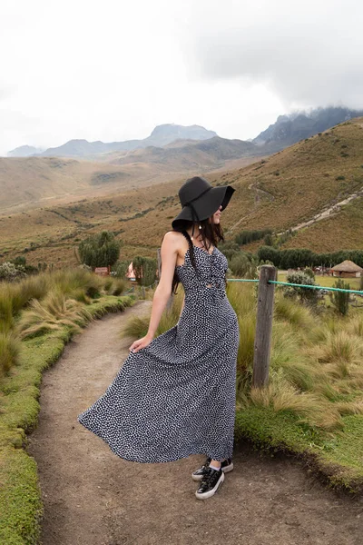 Doğada yürüyüş yapan genç bir Latin kadın, şapka ve uzun bir elbise giyiyor, yaşam tarzı ve özgürlüğün tadını çıkarıyor.