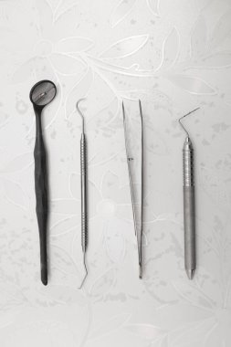 Metal lekesiz cımbız ve diş aynası ile çalışma masasının detayları, dişçiye müdahale için sipariş edilen profesyonel araç gereçler