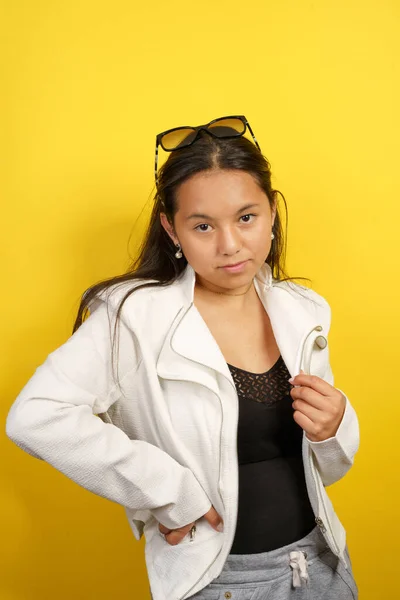 年轻的拉丁女孩 身穿夹克和太阳镜 模特在演播室穿着很酷的配饰 年轻貌美 有黄色背景的肖像 — 图库照片