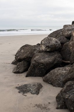 Gündüzleri büyük kayalar, kum ve bulutlu gökyüzü, arka planda okyanus, turistik yer, Ekvador sahillerindeki doğal güzellik.