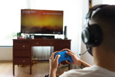 Person playing video game with remote control, wireless headphones and television screen, modern hobbies, electronic devices for leisure, Gamer