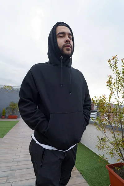 young latin man with beard wear sports hooded sweater, urban fashion city lifestyle, model posing