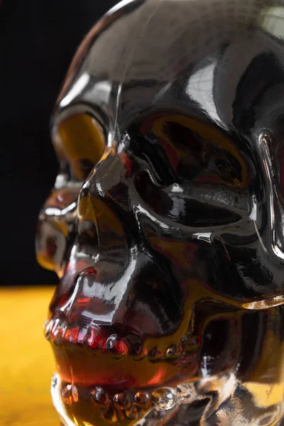 details of a glass bottle in the shape of a skull with a drink inside in the studio, decanter, decorative objects