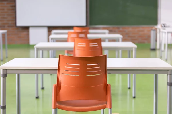 decoration of the interior of a classroom in a school with desks, colored chairs and blackboard. teaching place with comfortable furniture