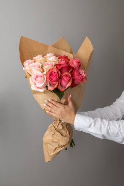 hands holding a bouquet of colorful roses, flower arrangement as a romantic gift, studio with detail in the petals, beauty of nature