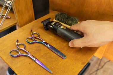 El, iş alanından saç kesimi ve fırça için profesyonel makas gibi kuaförlük araçlarıyla birlikte bir jilet alıyor.