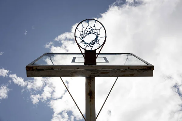 Aşağıdan perspektifli bir sahada basketbol potası, bulutlar, spor ve hobiler içeren güneşli bir arka plan, duvar kağıdı.