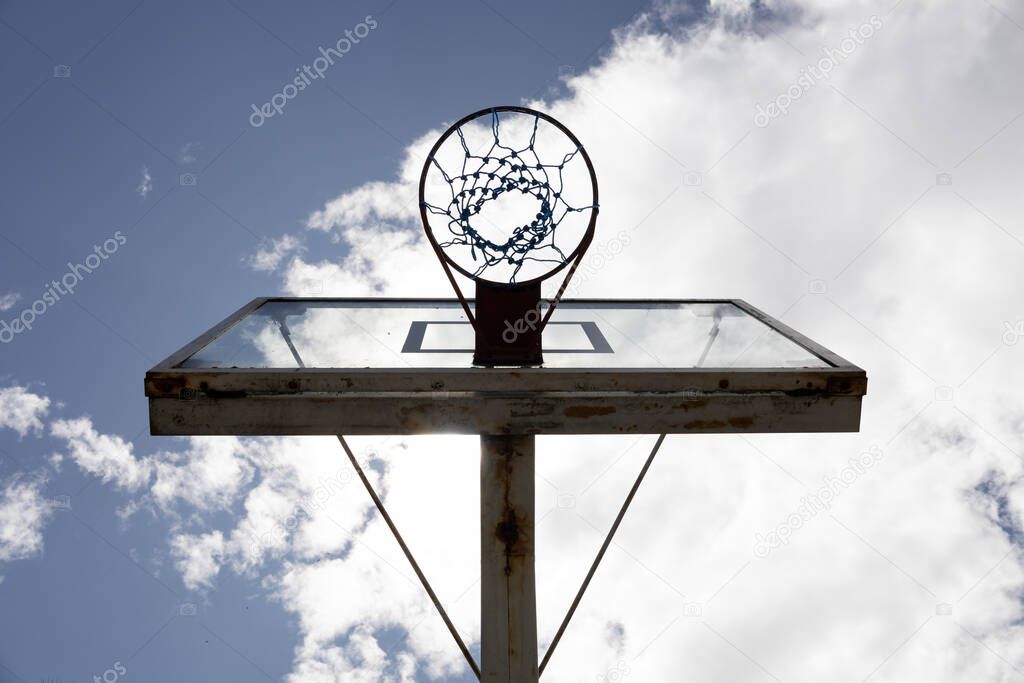 basketball hoop on a court with perspective from below, sunny sky background with clouds, sports and hobbies object, wallpaper