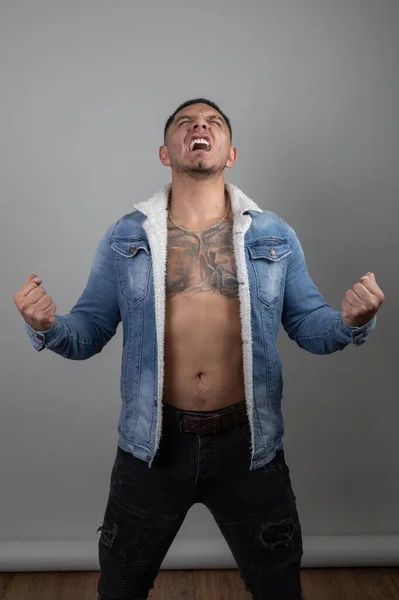 Молодий Латинський Чоловік Кричить Татуюванням Торсі Носить Джинсову Куртку Студії — стокове фото
