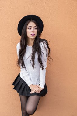 Stüdyoda modaya uygun şapka ve elbise giyen genç kız, stüdyo portresi, uzun dalgalı saçlı latin kişi, şık doğal güzellik